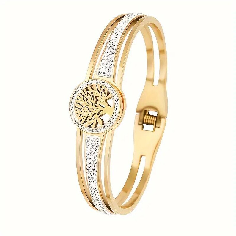 May include: Gold-tone bangle bracelet with a tree of life design and clear crystal accents.
