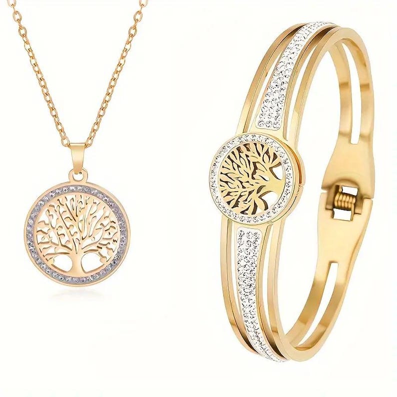 May include: A gold-tone necklace and bracelet set featuring a tree of life pendant and matching bracelet with clear crystal accents.