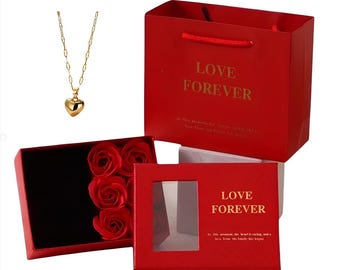 May include: A red gift box with a gold inscription that reads "Love Forever". The box is open to reveal a smaller red box with a clear window and a gold heart necklace inside. The smaller box also has the inscription "Love Forever".
