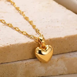 Pu&ograve; includere: Una collana a catena d'oro con un ciondolo a forma di cuore. Il ciondolo &egrave; liscio e lucido.