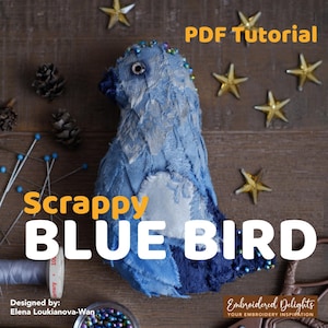 Pode incluir: Um pássaro azul feito à mão de tecido com o texto "Scrappy BLUE BIRD" e "PDF Tutorial". O pássaro tem uma mancha branca no peito e é decorado com contas. A imagem também inclui decorações de estrelas douradas e materiais de costura.