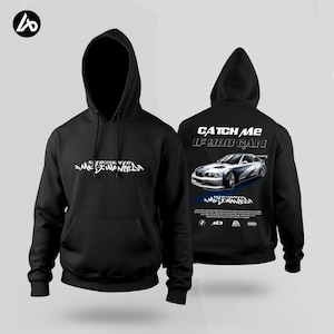 Puede incluir: Sudadera con capucha negra con el texto blanco "Need for Speed Most Wanted" en la parte delantera. La parte trasera muestra un gráfico de coche y el texto "Catch Me If You Can". Una sudadera para los fanáticos de los juegos de carreras.
