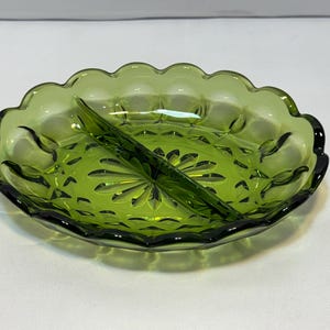 Puede incluir: Un plato de servir dividido de vidrio verde con borde festoneado. El plato tiene un divisor central y un patrón de estrella en la base. El vidrio es de un tono verde vibrante.
