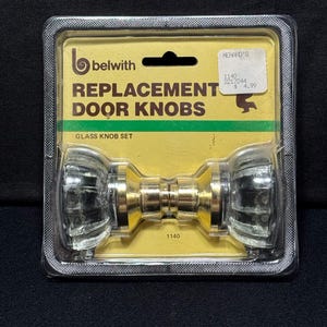 Puede incluir: Un juego de pomos de puerta de repuesto Belwith de cristal transparente con bases de metal dorado, en su embalaje de plástico original. La tarjeta amarilla muestra el texto: belwith, REPLACEMENT DOOR KNOBS, GLASS KNOB SET y 1140.