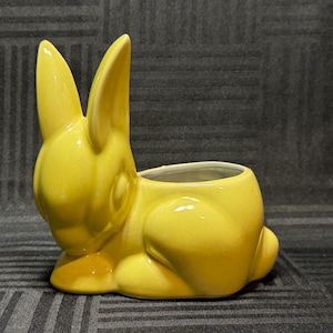 Può includere: Un set di tre tazze in ceramica con una glassa screziata color crema. Ogni tazza presenta un disegno dipinto a mano diverso: una foglia blu e verde, un fiore giallo e una bacca rossa. Le tazze hanno una forma semplice e arrotondata.