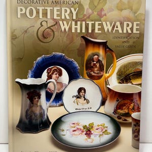 May include: A hardcover book titled Decorative American Pottery & Whiteware Identification and Value Guide by Jeanie Klamm Wilby. The cover features a collage of antique ceramic pitchers and plates decorated with portraits, floral motifs, and fish.