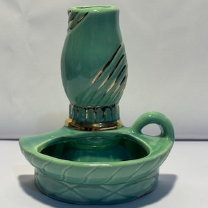 May include: A green ceramic candle holder with a gold trim. The holder has a small bowl for the candle and a tall, slender vase-like top.