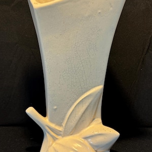 May include: A white ceramic vase with a crackled glaze and a stylized leaf design at the base.