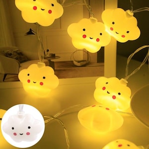 May include: A string of LED lights featuring multiple yellow cloud-shaped covers, each with a smiling face, black eyes, and pink cheeks. One cloud is shown unlit in a white circular inset, displaying the same smiling face and pink cheeks.