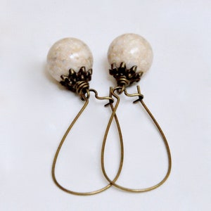 May include: A pair of earrings with white marble-like beads and antique gold-toned wire hoops.