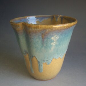 May include: A ceramic vase with a blue and brown glaze. The vase has a fluted rim and a rounded body.