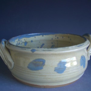 May include: A white ceramic serving bowl with two handles. The bowl has a blue glaze with a speckled pattern.