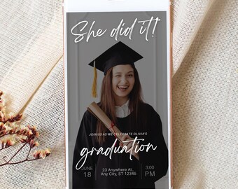 May include: A smartphone displays a graduation announcement. The image features a graduate in a cap and gown, winking and holding a diploma. Text on the screen reads "She did it!" and "graduation", along with date, time, and location details.