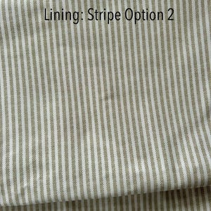 May include: Close-up of fabric with vertical stripes in off-white and olive green. The text "Lining: Stripe Option 2" is printed in black at the top. The fabric is folded over, showing the pattern and texture.