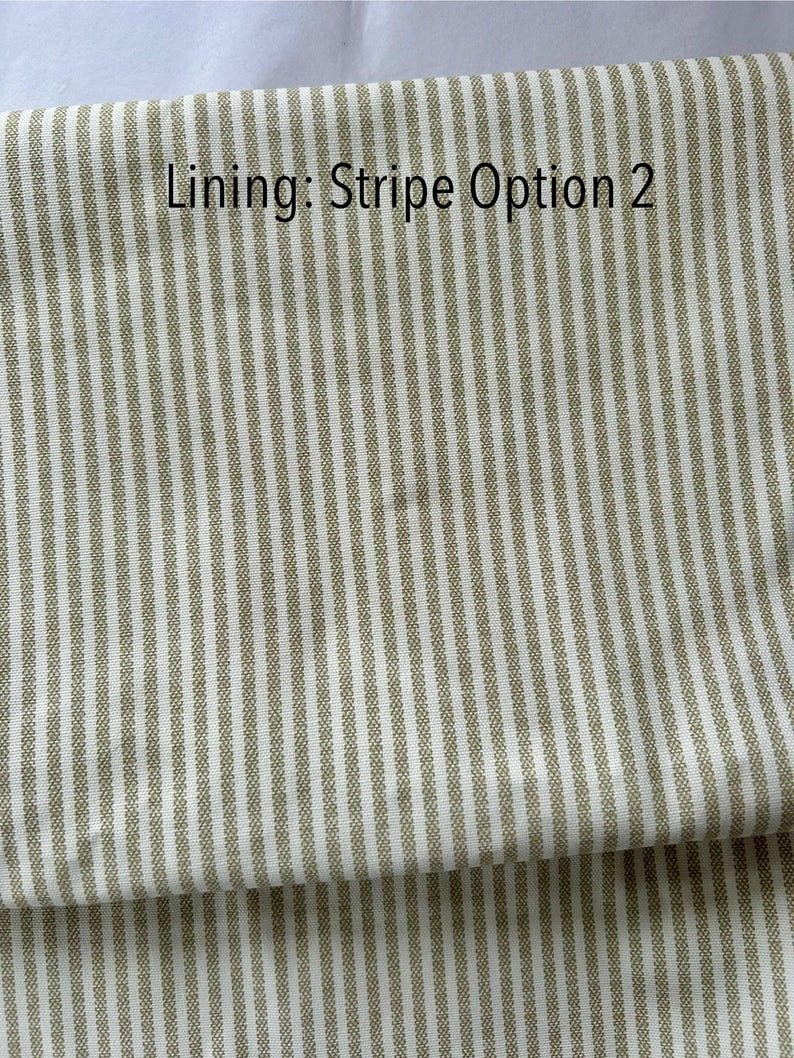 May include: Close-up of fabric with vertical stripes in off-white and olive green. The text "Lining: Stripe Option 2" is printed in black at the top. The fabric is folded over, showing the pattern and texture.