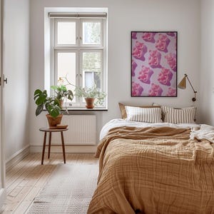 Pode incluir: Interior de quarto com uma cama coberta por um cobertor texturizado cor de mostarda e almofadas listradas. Um p&ocirc;ster emoldurado com ursinhos de goma rosa est&aacute; pendurado acima da cama. Uma pequena mesa de madeira suporta uma planta em vaso.
