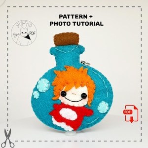 May include: A teal felt potion bottle with a cartoon character design. The bottle has a brown cork and a small silver ring. The character has orange hair and a red and white outfit. The text "PATTERN + PHOTO TUTORIAL" is at the top.