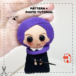 May include: A handmade felt doll keychain featuring a character with a purple head covering, black robe, and a wand. The doll has large black eyes and a stern expression. The text "PATTERN + PHOTO TUTORIAL" is visible.