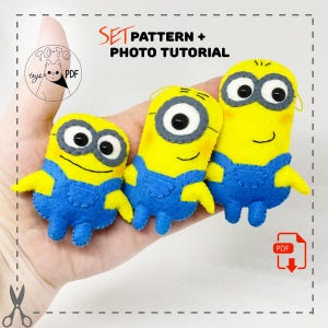 Puede incluir: Un conjunto de tres personajes de Minion de fieltro, cada uno con una expresión diferente. Los Minions son amarillos con monos azules y gafas de protección. El conjunto incluye un patrón PDF y un tutorial fotográfico para hacer tus propios Minions.