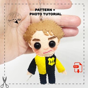 Könnte beinhalten: Handgemachte Filzpuppe einer Figur mit braunen Haaren, großen schwarzen Augen und einem kleinen rosa Mund. Die Puppe trägt eine schwarz-gelbe Uniform mit einem "H"-Emblem. Der Text "PATTERN + PHOTO TUTORIAL" ist sichtbar.