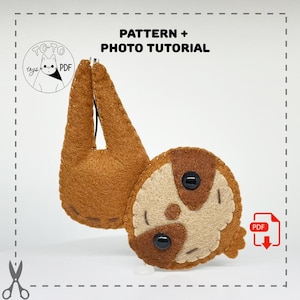 May include: A brown and beige felt sloth hanging upside down. The sloth has black button eyes and a stitched smile. The image includes the text "PATTERN + PHOTO TUTORIAL" and a logo with the text "TOTO toys PDF".