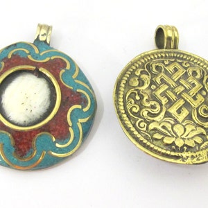 May include: Two antique pendants. One is round with a turquoise and red enamel design, a gold-colored border, and a white center. The other is a gold-colored, circular pendant with an embossed pattern.
