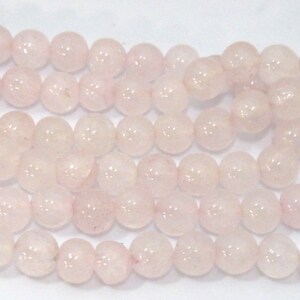 Pu&ograve; includere: Primo piano di fili di perline rotonde di quarzo rosa chiaro. Le perline sono lisce e traslucide. Sono infilate, pronte per la creazione di gioielli o altri progetti creativi. Le perline sono di un colore naturale e delicato.