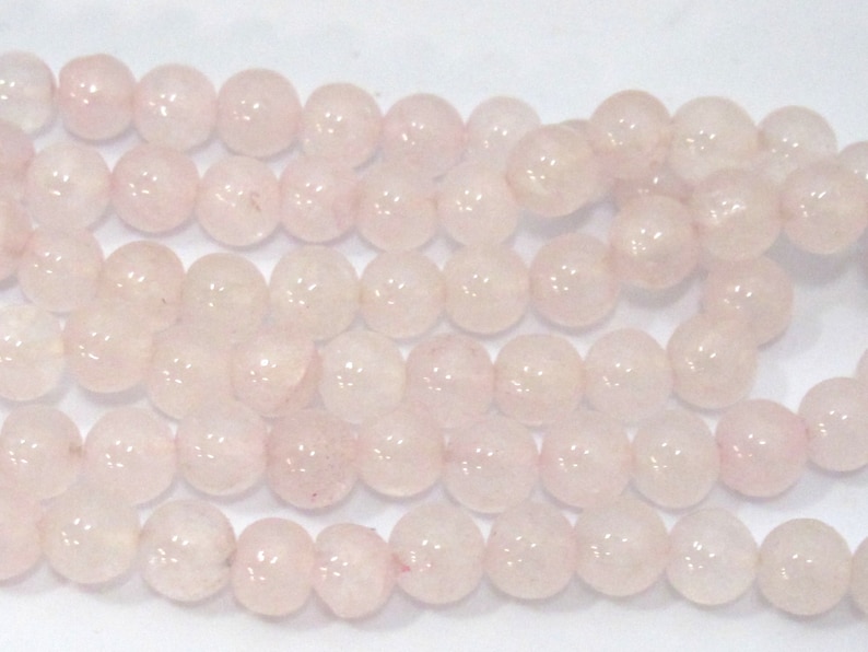 Pu&ograve; includere: Primo piano di fili di perline rotonde di quarzo rosa chiaro. Le perline sono lisce e traslucide. Sono infilate, pronte per la creazione di gioielli o altri progetti creativi. Le perline sono di un colore naturale e delicato.