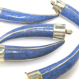 May include: Four horn-shaped pendants made of deep blue lapis lazuli stone with metallic silver-toned caps and thin metallic inlay lines running along the curved length of each piece, each featuring a small loop at the top for attachment.