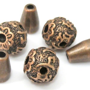 May include: A collection of copper-colored beads and cone-shaped findings. The round beads feature an ornate floral design, while the cones have a smooth, tapered shape. These jewelry-making components are ideal for crafting necklaces, bracelets, and earrings.
