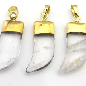 May include: Three clear quartz crystal pendants with gold-colored metal caps and loops. The pendants are shaped like small tusks or horns, with a polished, translucent appearance. The gold caps add a touch of elegance to the natural crystal.