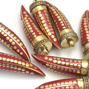 May include: A collection of red and gold horn-shaped pendants. Each pendant features a red body with gold dot and line patterns, and is capped with a gold-colored metal top. The pendants have a loop for hanging.