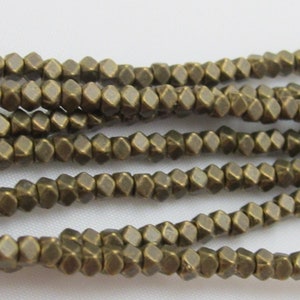 May include: Strands of small, bronze-colored, faceted beads. The beads have a geometric shape and are strung together, creating a textured surface. The beads are a warm, metallic color.