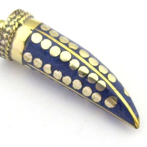 May include: A pendant with a horn shape, featuring a brass-colored top and tip. The body is navy blue with gold-colored circular accents. A gold-colored line runs down the center of the pendant.