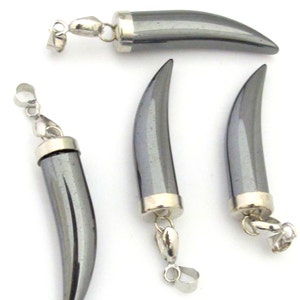 May include: Four hematite pendants in the shape of a curved horn. Each pendant has a silver-colored metal cap and a loop for attaching to a chain. The pendants are a dark, metallic gray color and are displayed against a white background.