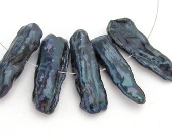 Può includere: Cinque perle barocche blu scuro infilate su un filo sottile. Le perle hanno una lucentezza iridescente con sfumature di verde e viola. Le forme irregolari delle perle contribuiscono al loro aspetto unico. Lo sfondo è bianco.