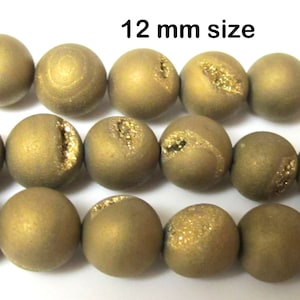 May include: Close-up of a strand of golden-brown, spherical beads. Each bead has a rough, textured surface and a sparkling, golden-colored geode-like inclusion. The text "12 mm size" is visible at the top.