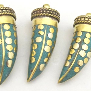 May include: Three horn-shaped pendants with brass caps and teal bodies adorned with gold-colored dots. The pendants have a textured brass top with a loop for hanging. The design is symmetrical, with the gold dots arranged in a pattern.