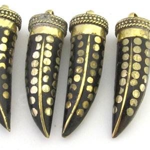 May include: Four horn-shaped pendants. Each pendant is black with gold-colored dot patterns and a gold-colored cap. The pendants are arranged on a white surface. The pendants are likely for jewelry making or crafting.