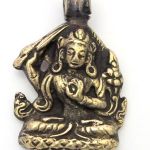 May include: A detailed, antique-style pendant featuring a seated figure with intricate details. The pendant is primarily gold-toned with darker accents, and has a loop at the top for a chain. The figure is in a meditative pose.