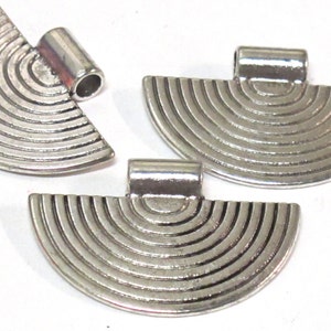 May include: Silver-toned metal pendants in a half-circle shape with concentric grooves. Each pendant has a small, cylindrical loop at the top for attaching to a chain or cord. The pendants are displayed against a white background.