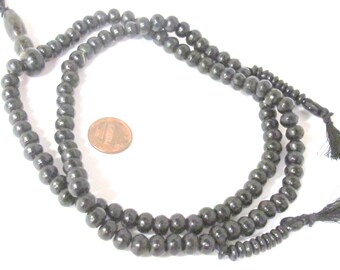 May include: Dark gray prayer beads with a tassel at each end. The beads are round and appear to be made of wood. A penny is next to the beads for size comparison.