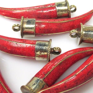 May include: A collection of horn-shaped pendants featuring a textured, speckled red surface. Each pendant is capped with a metallic silver-toned fitting that includes a small circular loop at the top for attachment, finished with a decorative rope-like edge.