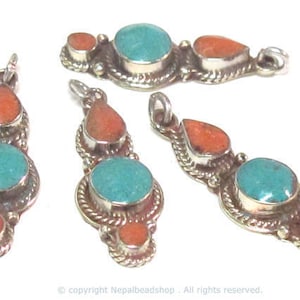 May include: Four silver pendants with turquoise and orange-red gemstones. The pendants have a variety of shapes, including oval and teardrop, and are set in a silver metal with a rope-like border. The gemstones are set in a silver metal.