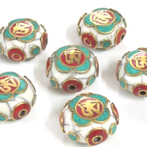 May include: Six white, spherical beads with a cracked texture. Each bead features a central design with a gold symbol, surrounded by turquoise and red accents. The beads have a metallic gold trim.