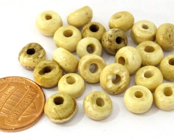 May include: A collection of off-white, round beads with a hole through the center. Some beads have darker spots. A U.S. one-cent coin is included for size reference. These beads are suitable for jewelry making and crafts.