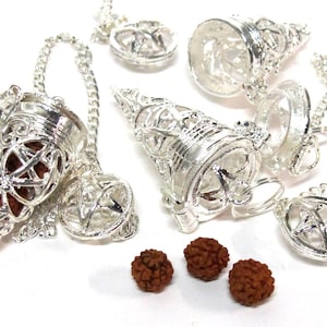 May include: Silver-colored pendulums with intricate filigree designs and chain attachments. The pendulums are cone-shaped and contain brown, textured beads. Several pendulums are displayed, along with loose beads.