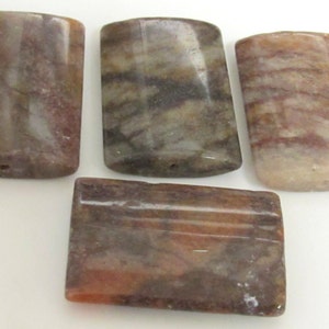 May include: Four rectangular, polished stone pendants in shades of brown, tan, and gray. Each pendant has a rounded top and a small hole for stringing. The stones display natural veining.