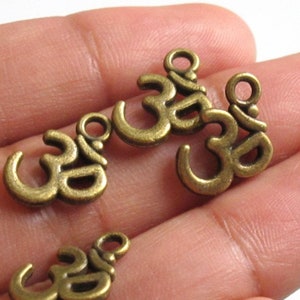 May include: Several bronze-colored Om symbol charms. Each charm features the sacred Om symbol, a spiritual icon in Hinduism and other religions. The charms have a loop at the top for easy attachment to jewelry or other crafts.