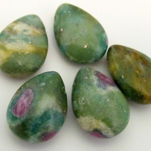 May include: Five teardrop-shaped gemstones in shades of green, with hints of yellow and red. The stones have a smooth, polished appearance and are arranged on a white surface. These gemstones could be used for jewelry making or other crafts.